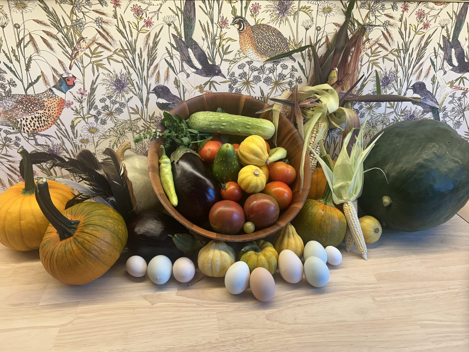 A harvest bowl of tomatoes, squash and cucumbers ringed by the flock's eggs